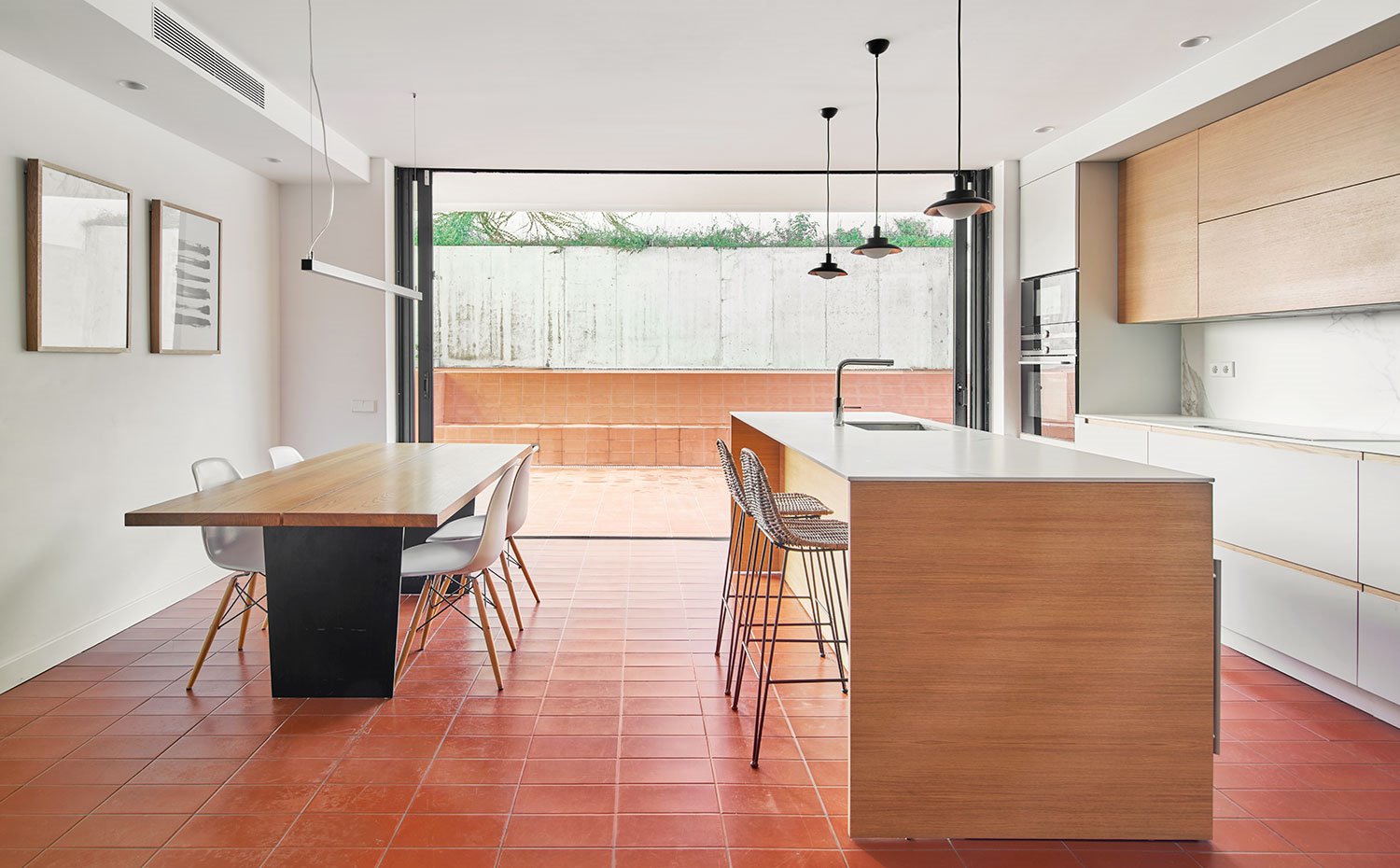 Comedor y cocina en un mismo ambiente, en carpitería hecha a medida en acabado madera y blanco, sillas de madera