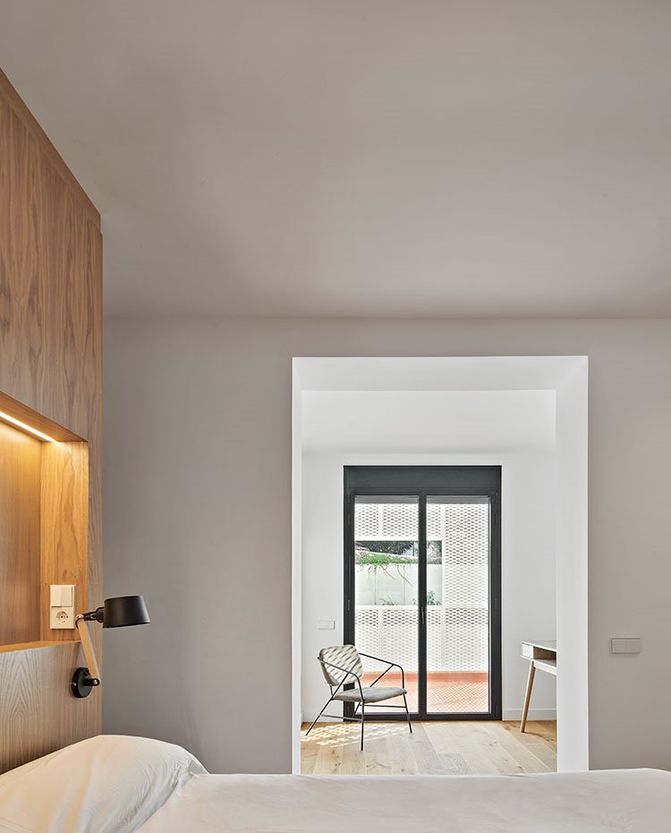 Dormitorio con cabecero de obra en madera natural, apliques a juego, aperturas entre ambientes sin cerramientos