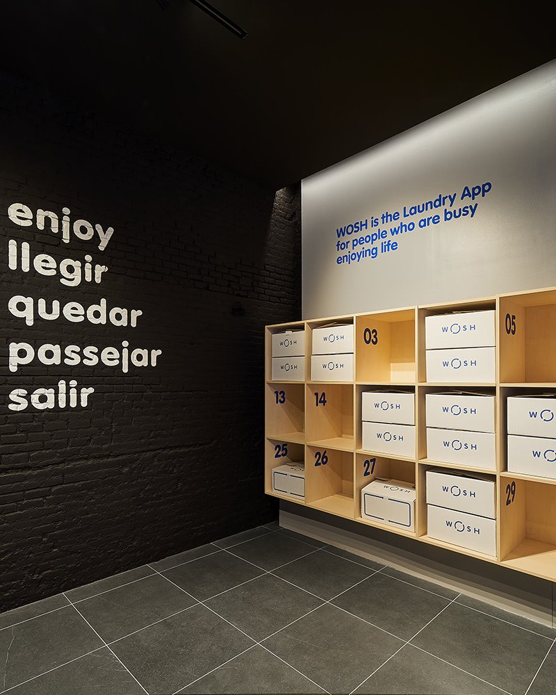 Lavanderia de diseño en Barcelona 6. El casillero de los encargos y la estantería del almacén, realizados con madera clara, ofrecen un punto de calidez a un proyecto imbuido de una imagen intencionadamente tecnológica.