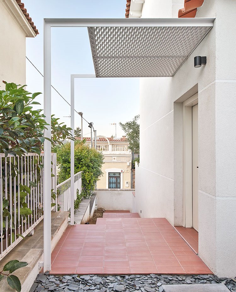 Entrada principal vivienda con porche en estructura metálica 