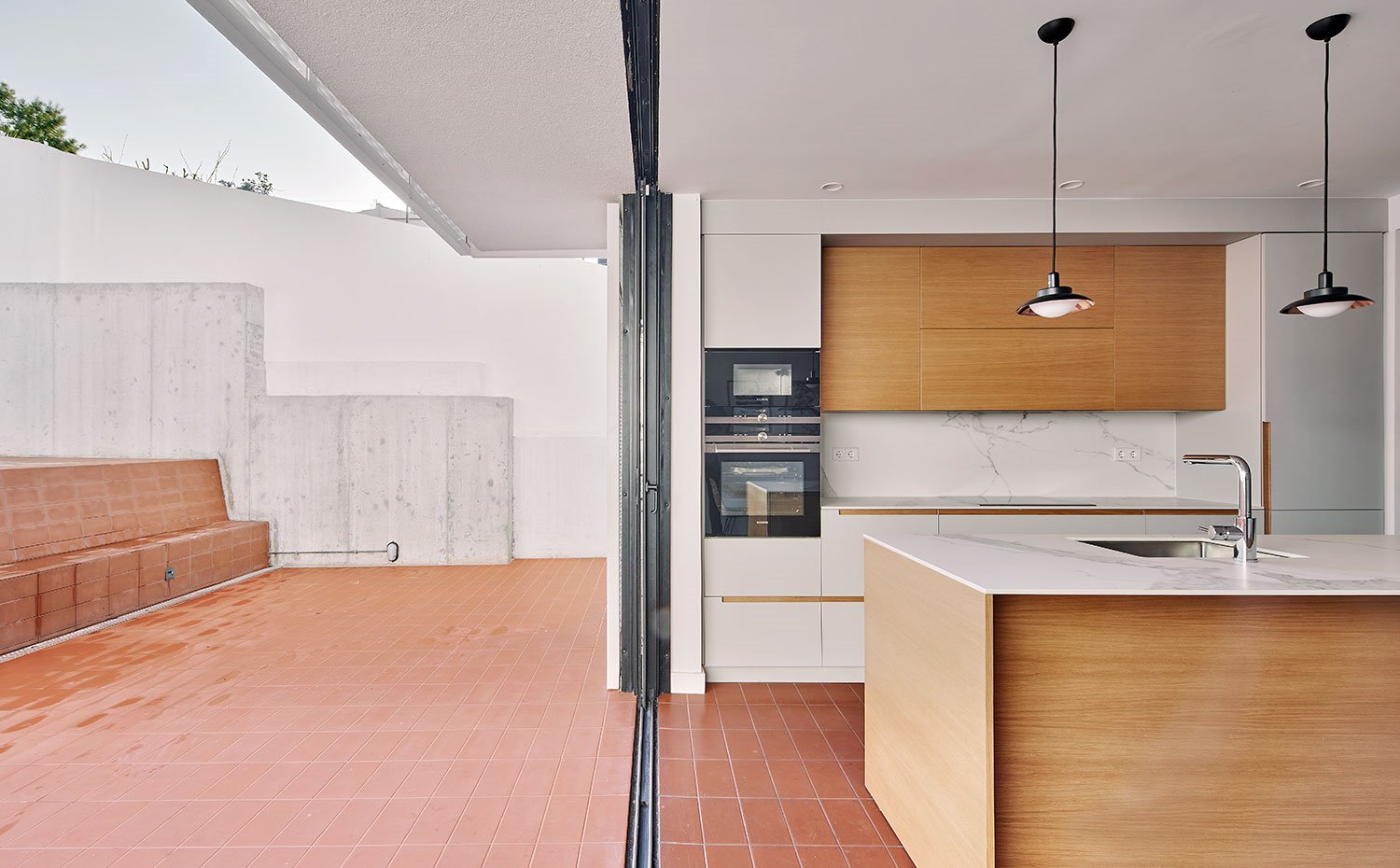 Exterior de la terraza trasera e interior de la cocina con isla 