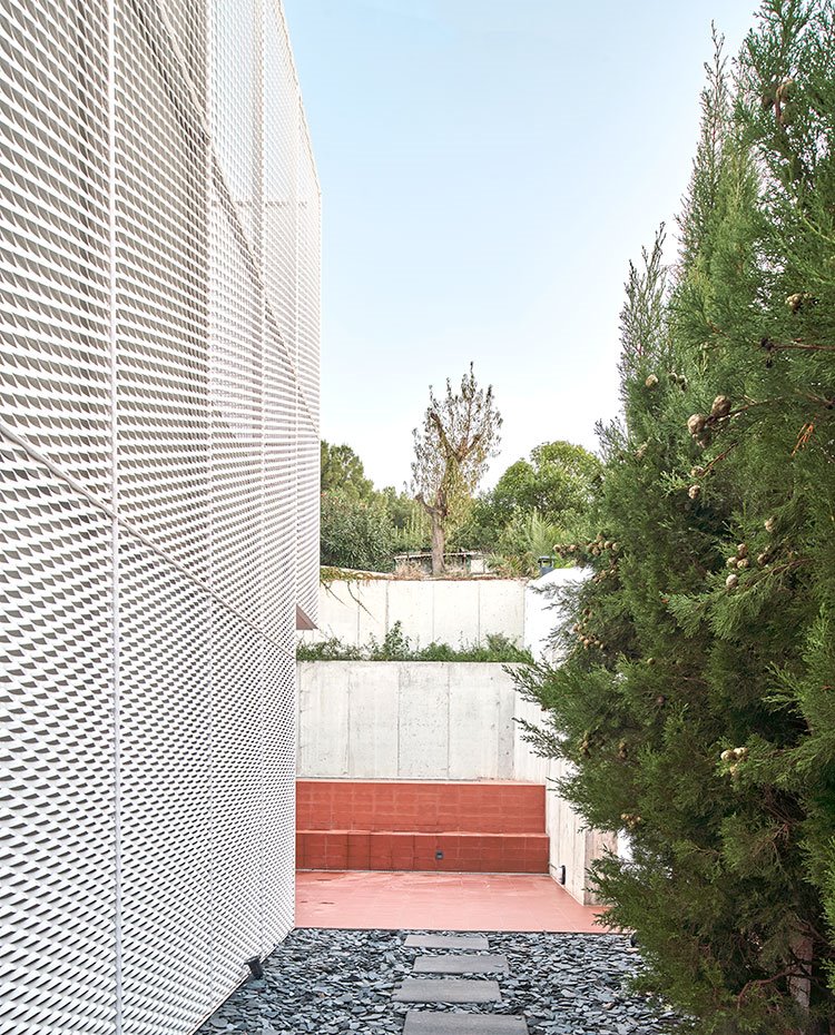 Lateral de la vivienda con piel metálica y camino en pizarra y bloques de hormigón