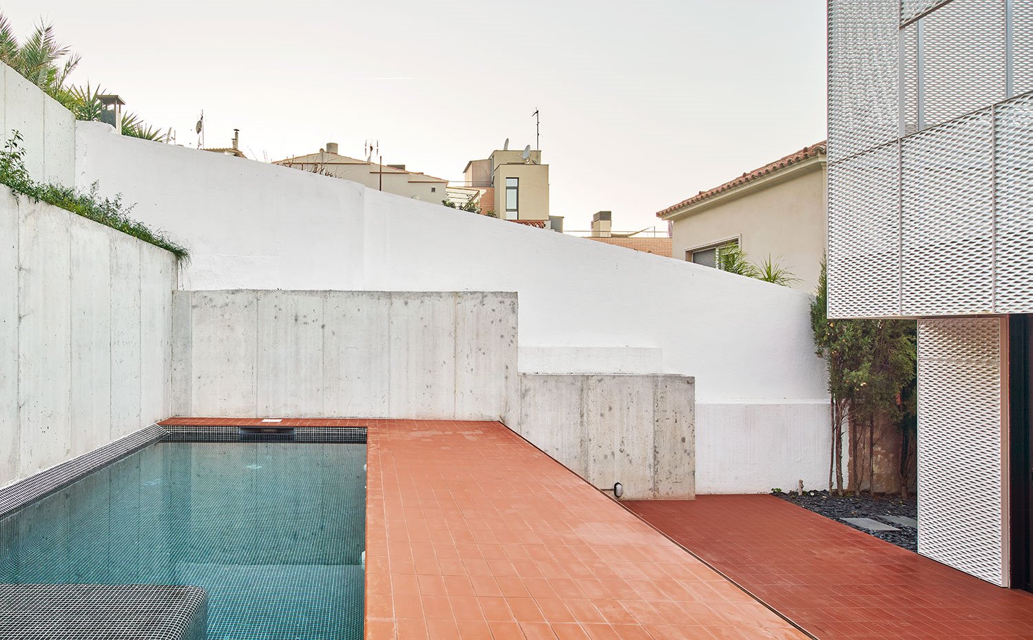 Piscina en gresite azul, suelo exterior con baldosas de gres, perímetro en hormigón al natural
