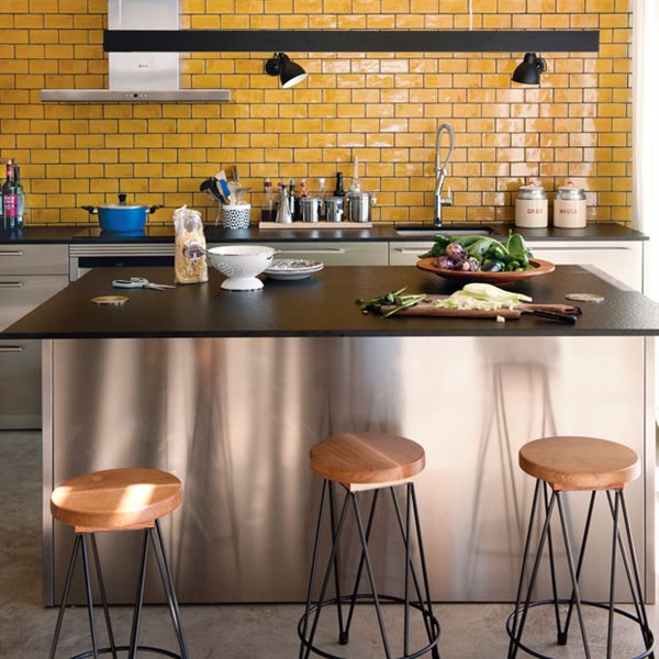 Cocina amarilla con encimera de granito negro y taburetes