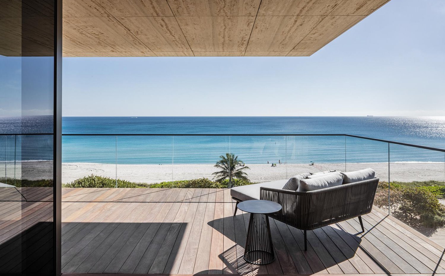 Terraza exterior con vistas a la playa con butaca y silla de exterior, suelo de madera