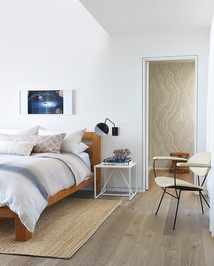 Dormitorio con cama en madera natural, mesilla en blanco, suelo de madera 