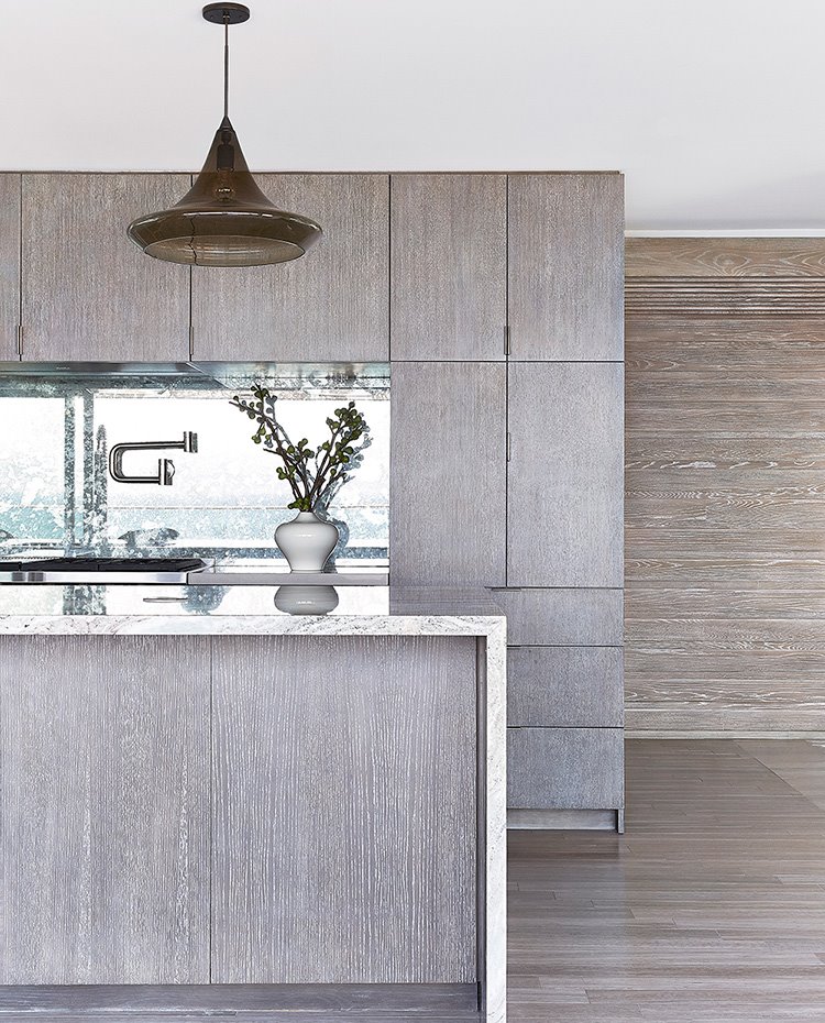Equipamiento de cocina en acabado madera, encimeras y salpicaderos en mármol, luminaria suspendida en marrón