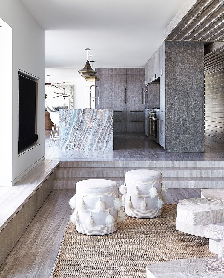 Salón hacia cocina, con chimenea integrada en pared, pavimento revestido de madera, isla de trabajo de mármol