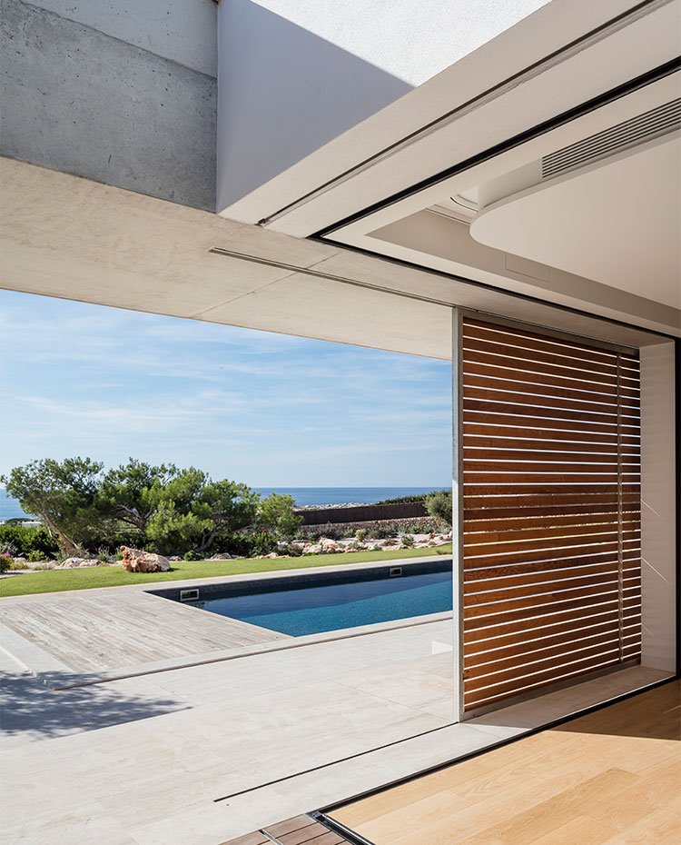Cerramientos correderos con listones de madera, piscina rectangular y vista al mar