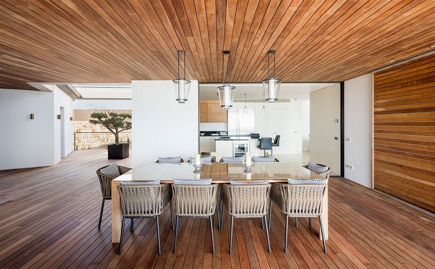 Comedor con suelo, paredes y techo recubiertos de madera, en zona semiabierta junto a cocina