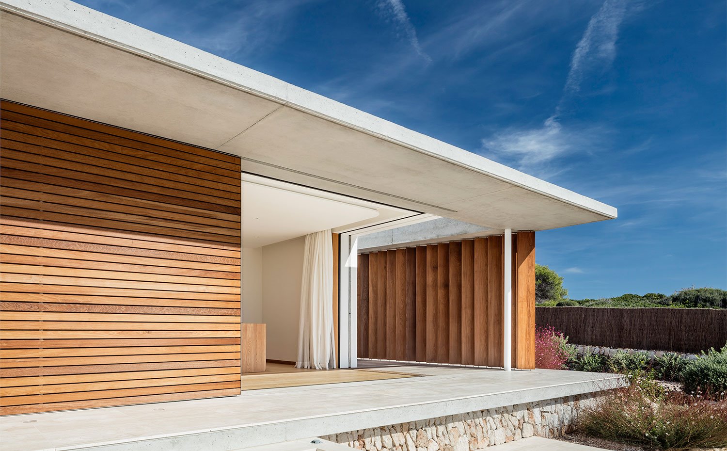 Detalle estructura con saliente de hormigón, cerramiento de madera y apertura hacia interior de vivienda