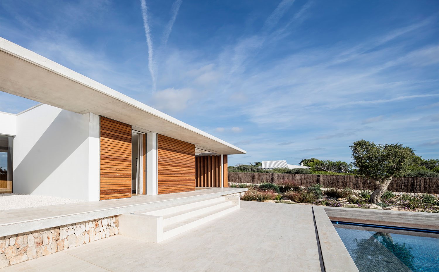Exterior de vivienda con piscina y escaleras revestidas de porcelánico, fachada de yeso, hormigón y madera