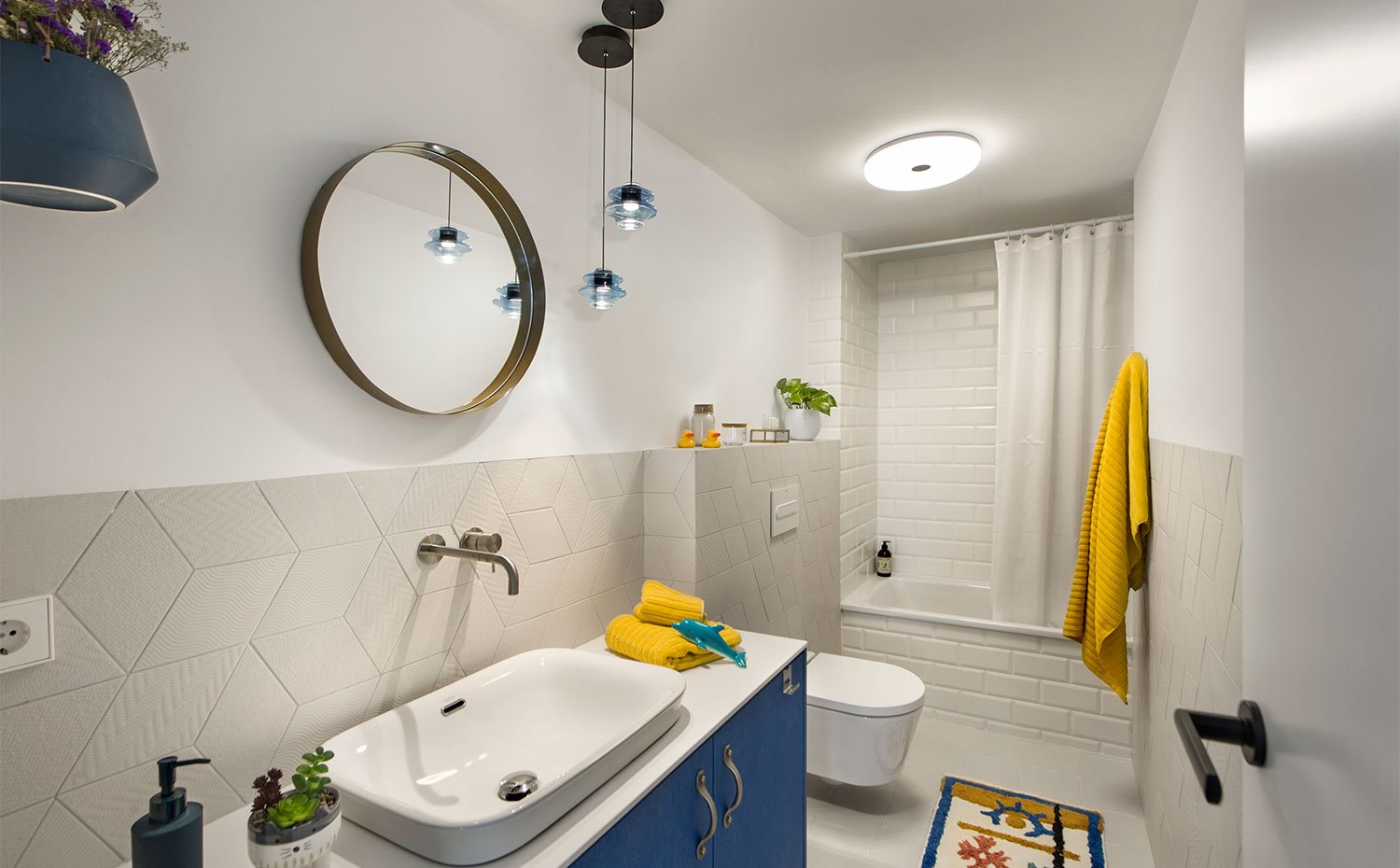 Cuarto de baño infantil con mobiliario en acabado azul y revestimiento de forma romboidal