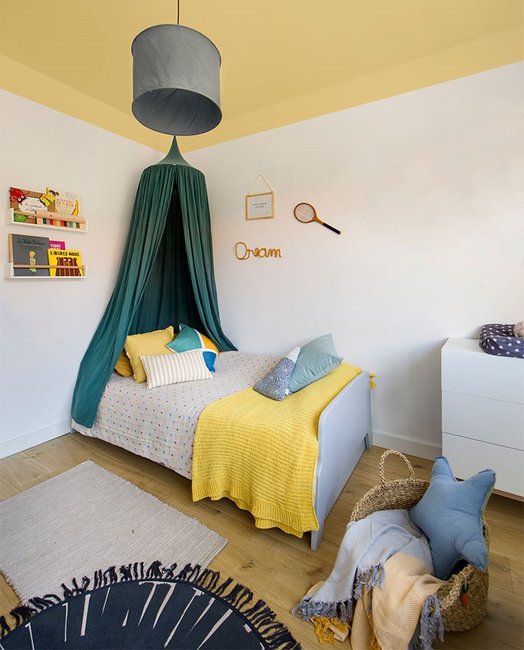 Dormitorio infantil con paredes en blanco y techo amarillo, mobiliario en blanco y gris