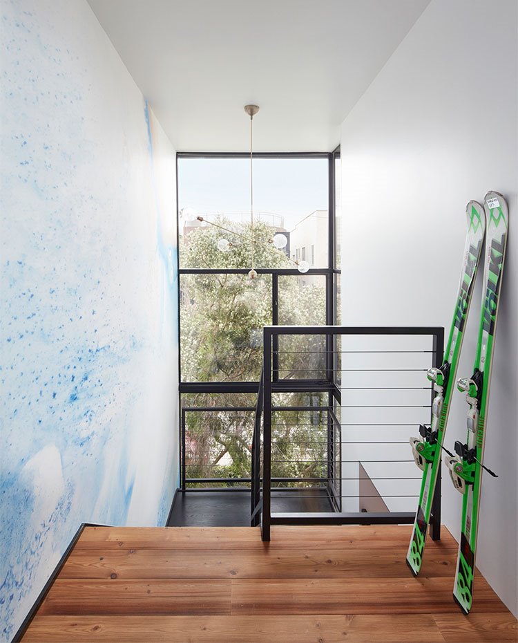 Pared de escalera con dibujo a modo de acuarela, gran apertura en fachada junto a hueco escalera, suelo de madera
