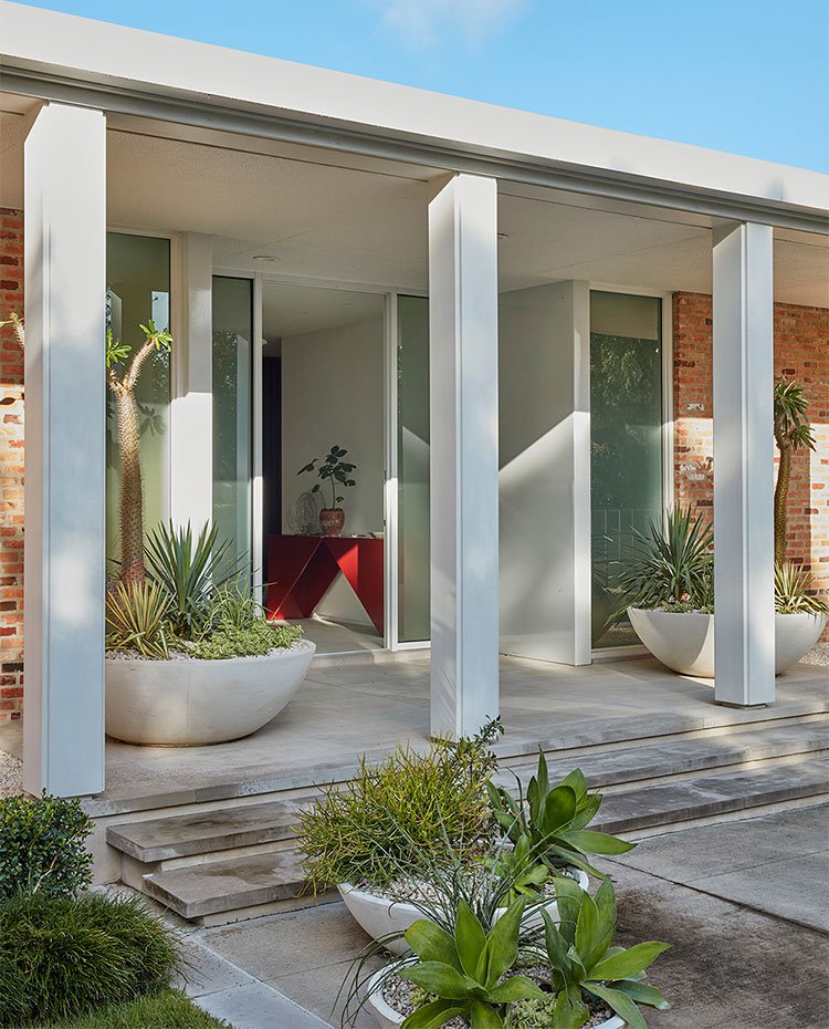 Entrada de la vivienda con estructura de hormigón y jardineras enmarcando entrada