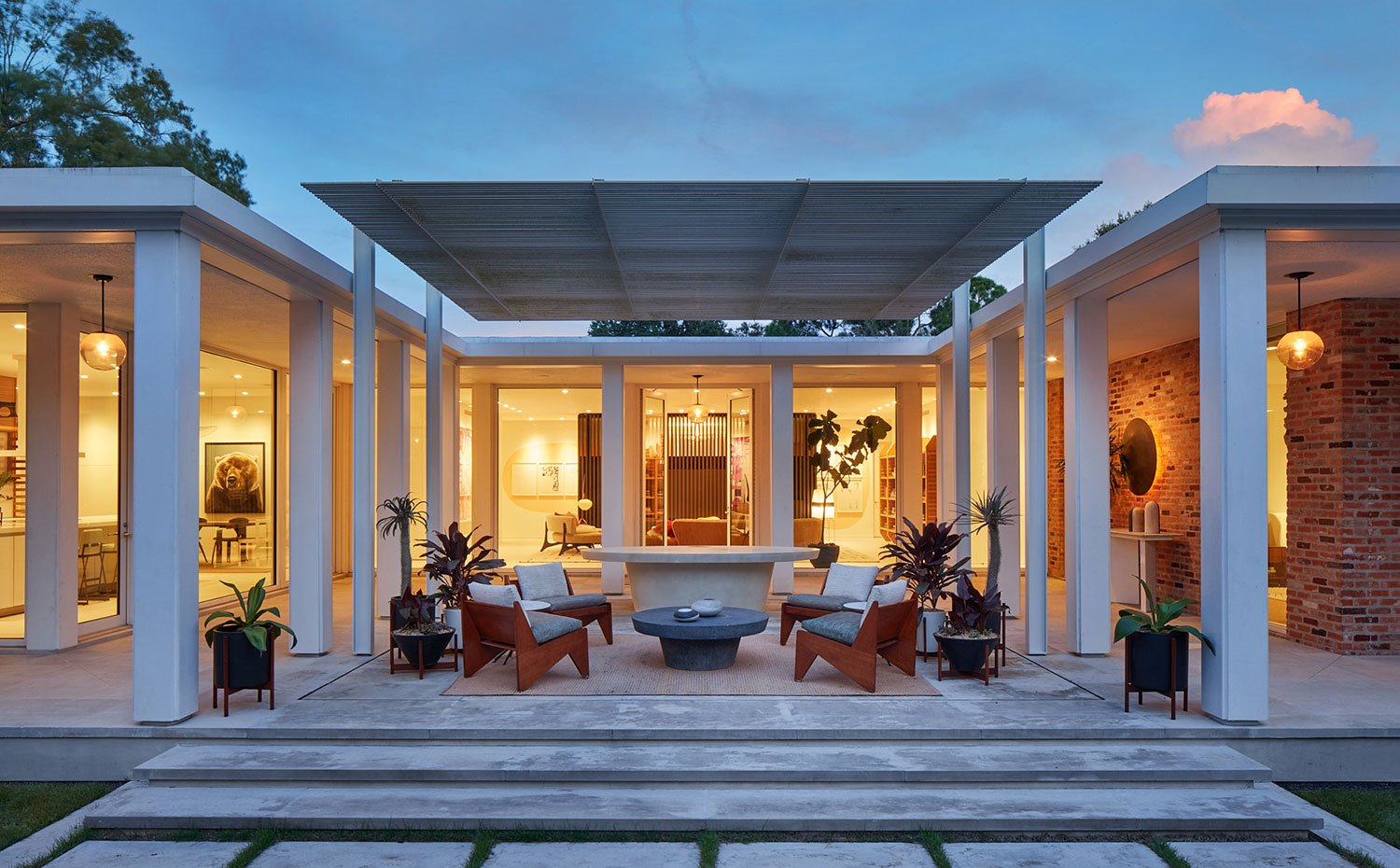 Terraza con zona de estar con butacas y mesas de piedra bajo pérgola