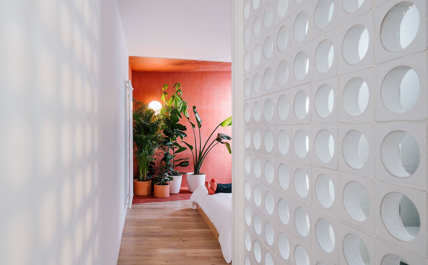Acceso a dormitorio con tabique con perforaciones circulares, suelo de madera