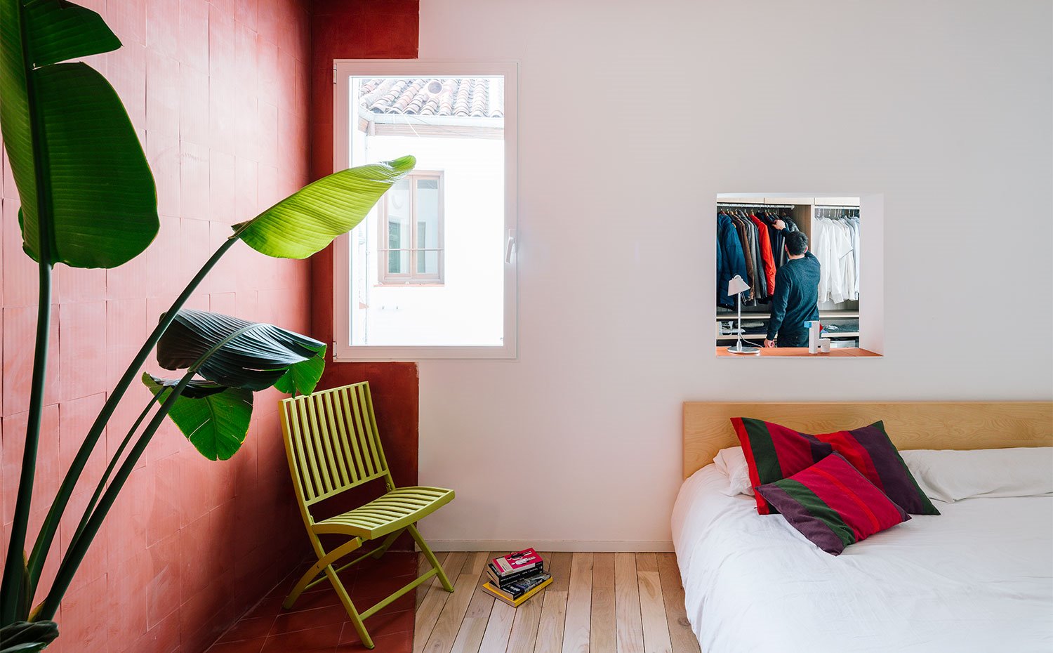 Dormitorio con hueco en pared hacia vestidor, silla en verde, pared en tonos teja