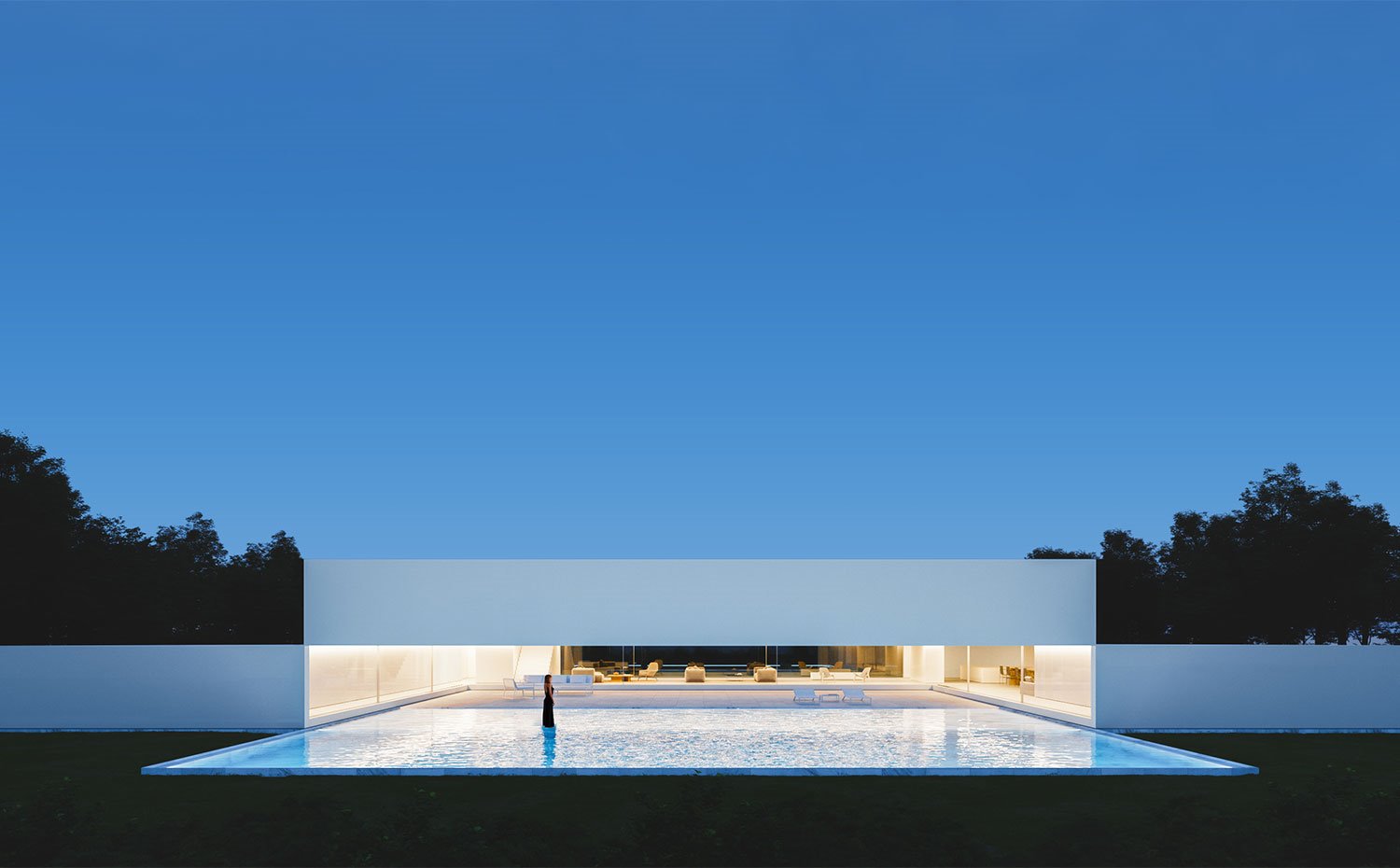 Vista nocturna de la vivienda con la amplia piscina frente al espacio interior