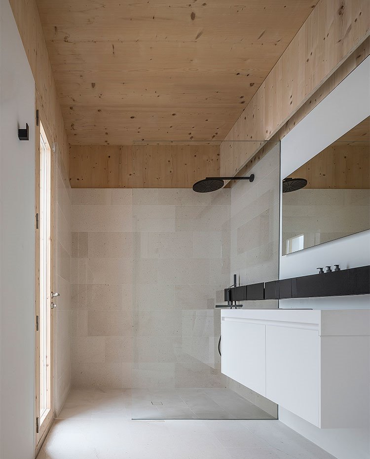 cuarto de baño con mobiliario en blanco y negro, techo de madera, grifería en negro