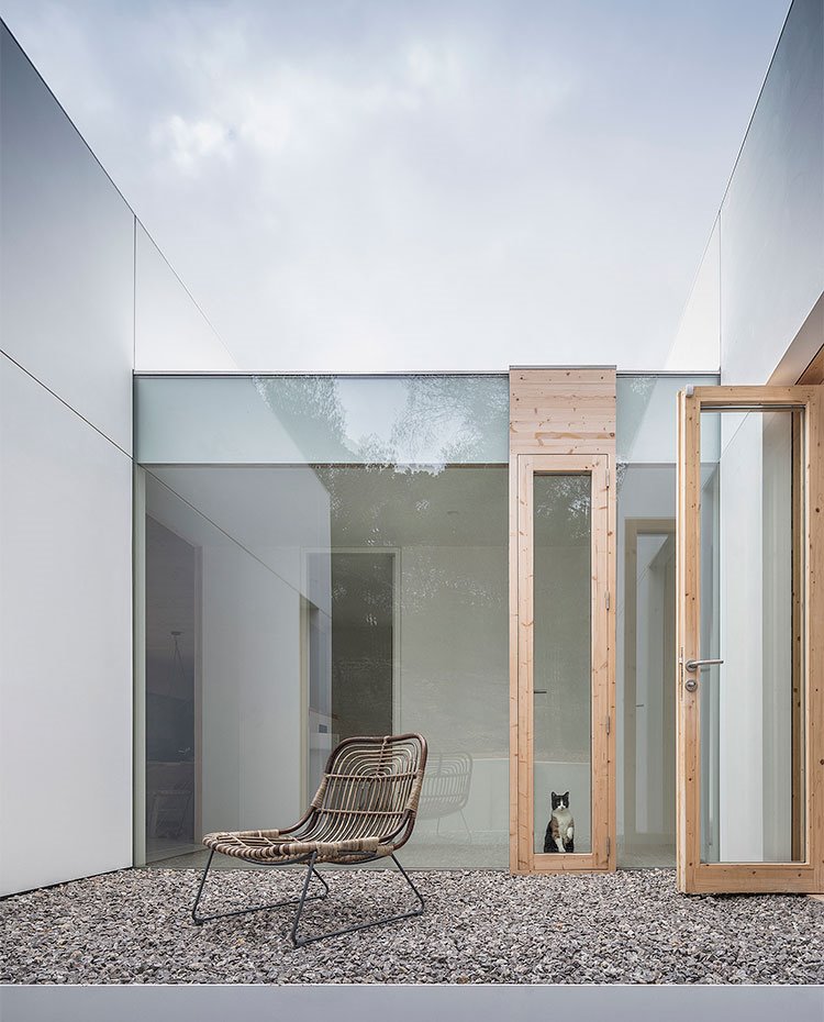 Zona exterior con piedras, zona de paso en cristal y perfilería de madera