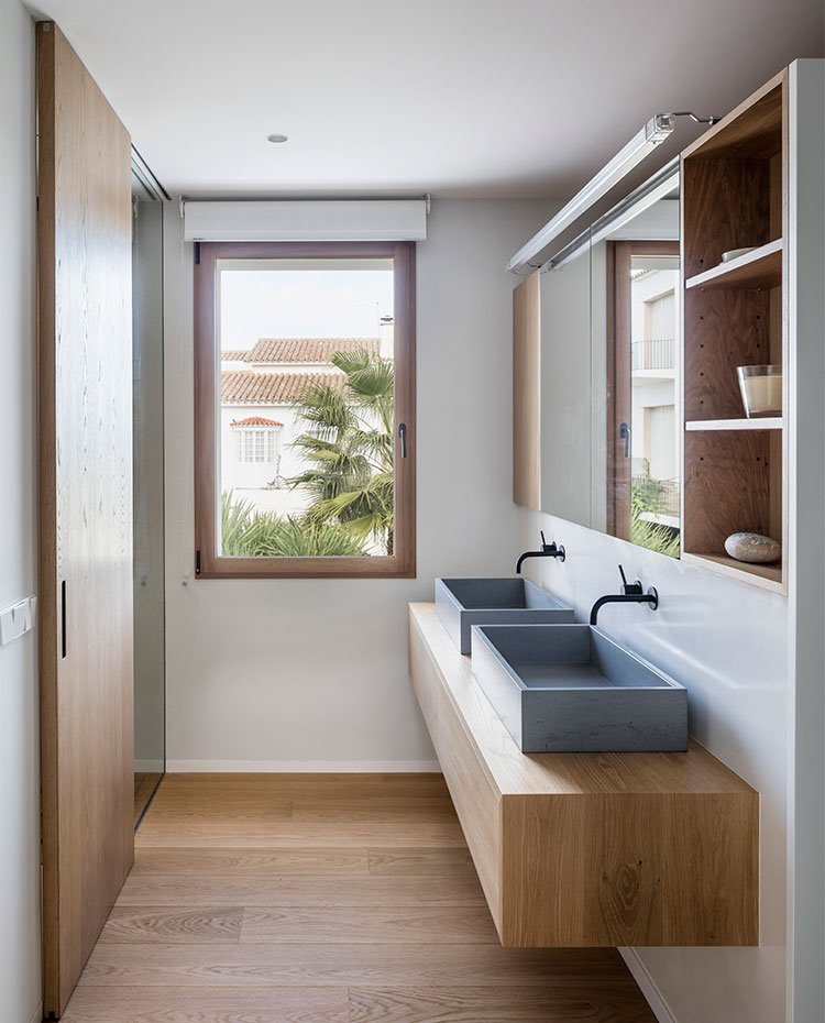 Cuarto de baño con suelo, puerta corredera y mobiliario en madera, pilas en gris