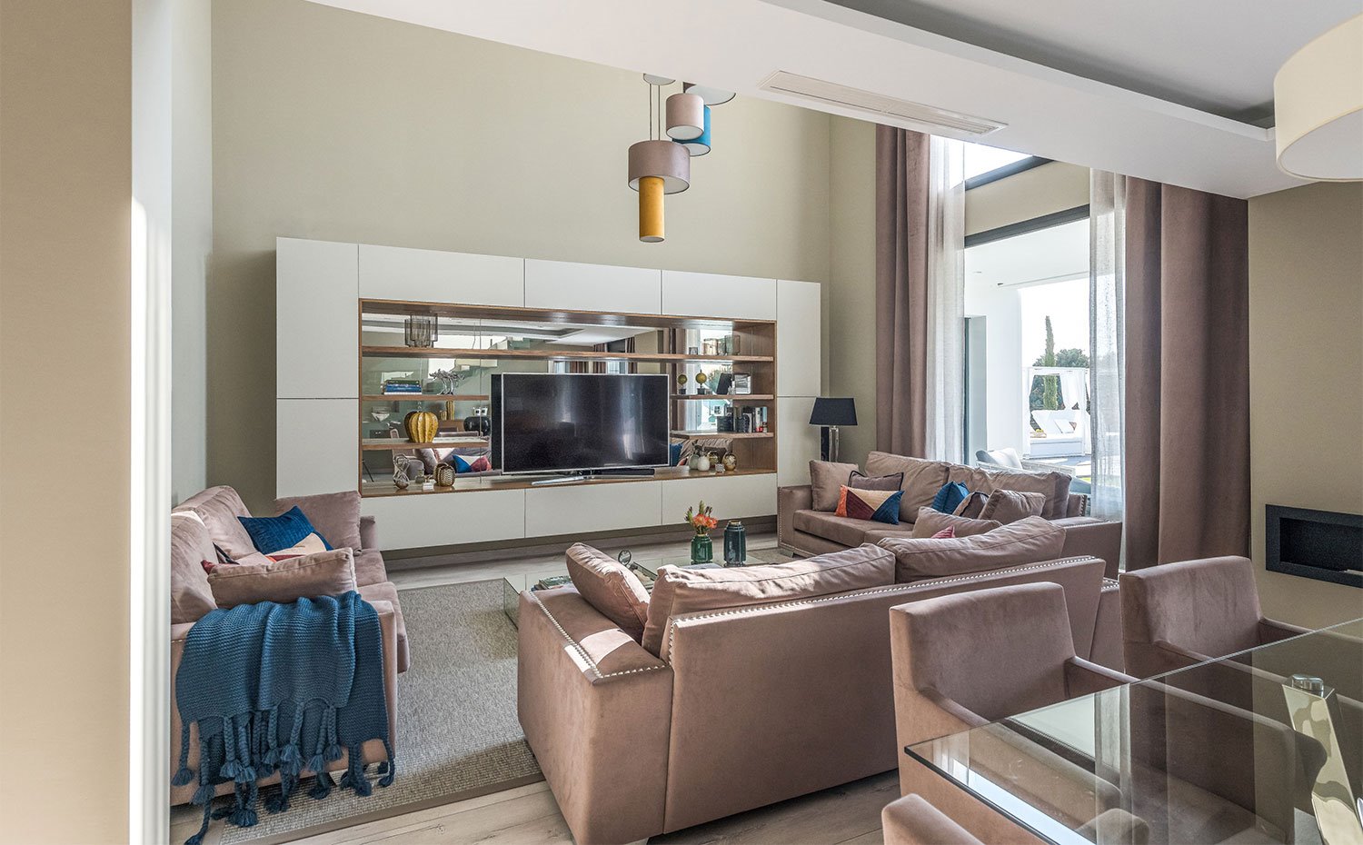 Salón con sofás en marrón y mueble en tonos crudos y revestido de espejos