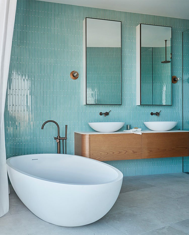 Cuarto de baño con bañera exenta y revestimiento en tonos turquesa