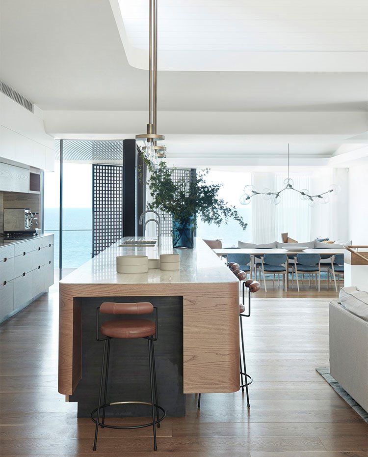 Extremo de isla central de cocina con taburete revestido en piel, suelo de madera