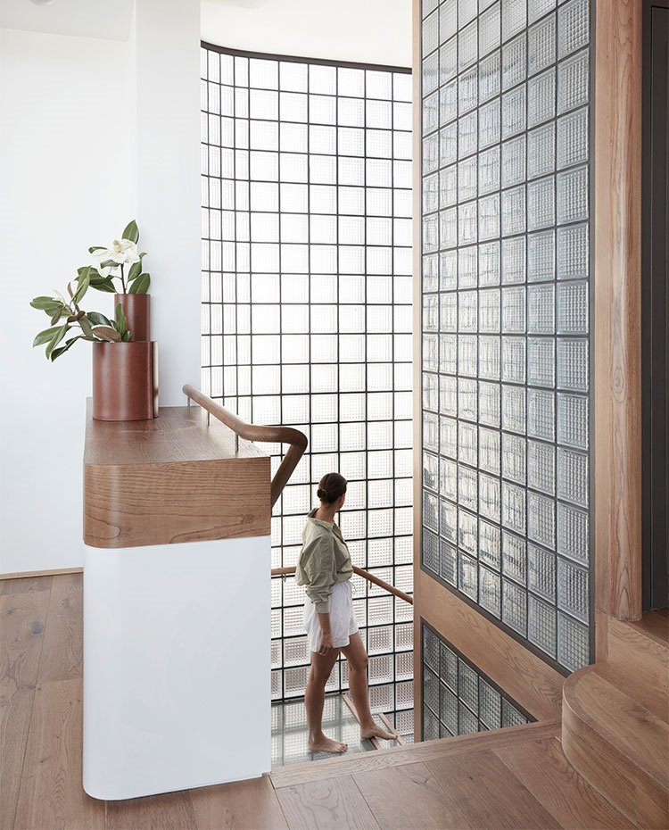 Parte superior de escalera con pared de pavés y pavimento de madera