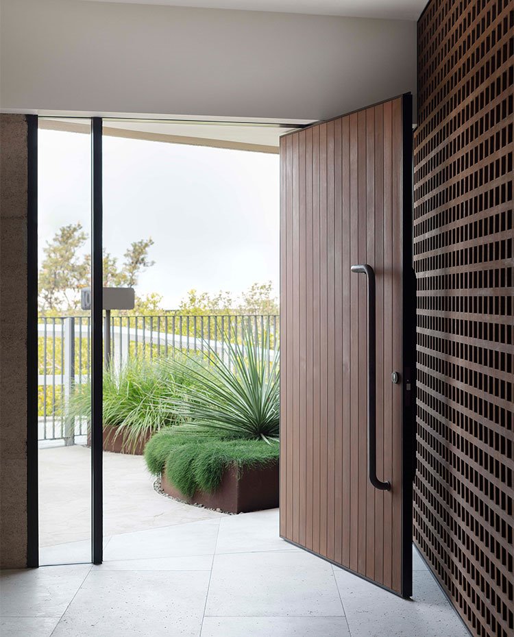Puerta de acceso en madera de gran amplitud, con celosía de madera en tabiquería