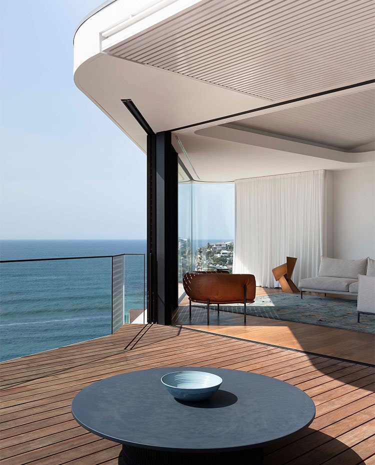 Terraza con suelo de madera y barandilla de cristal con acceso a salón