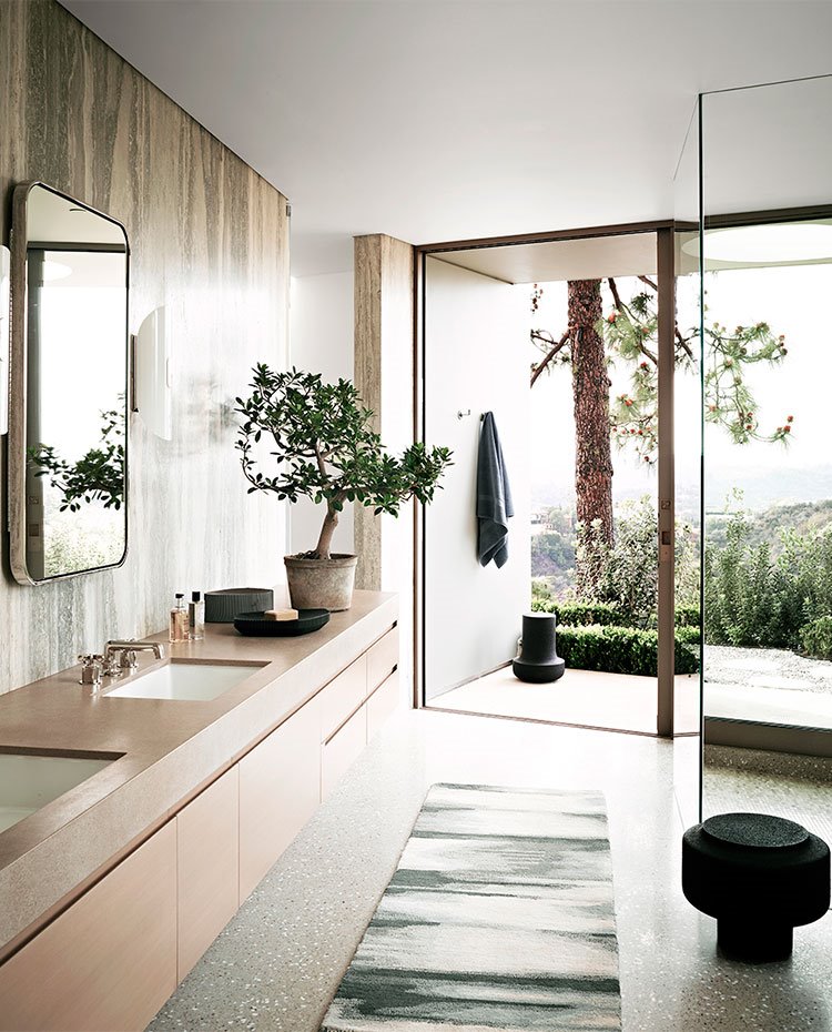 Cuarto de baño con pared en mármol, mueble de lavabo suspendido, cerramientos de ducha en cristal transprarente