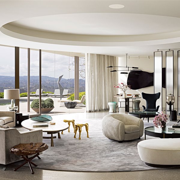 Salón con disposición circular, cerramientos de cristal, mobiliario contemporáneo con sofás curvos y chimenea revestida de mármol