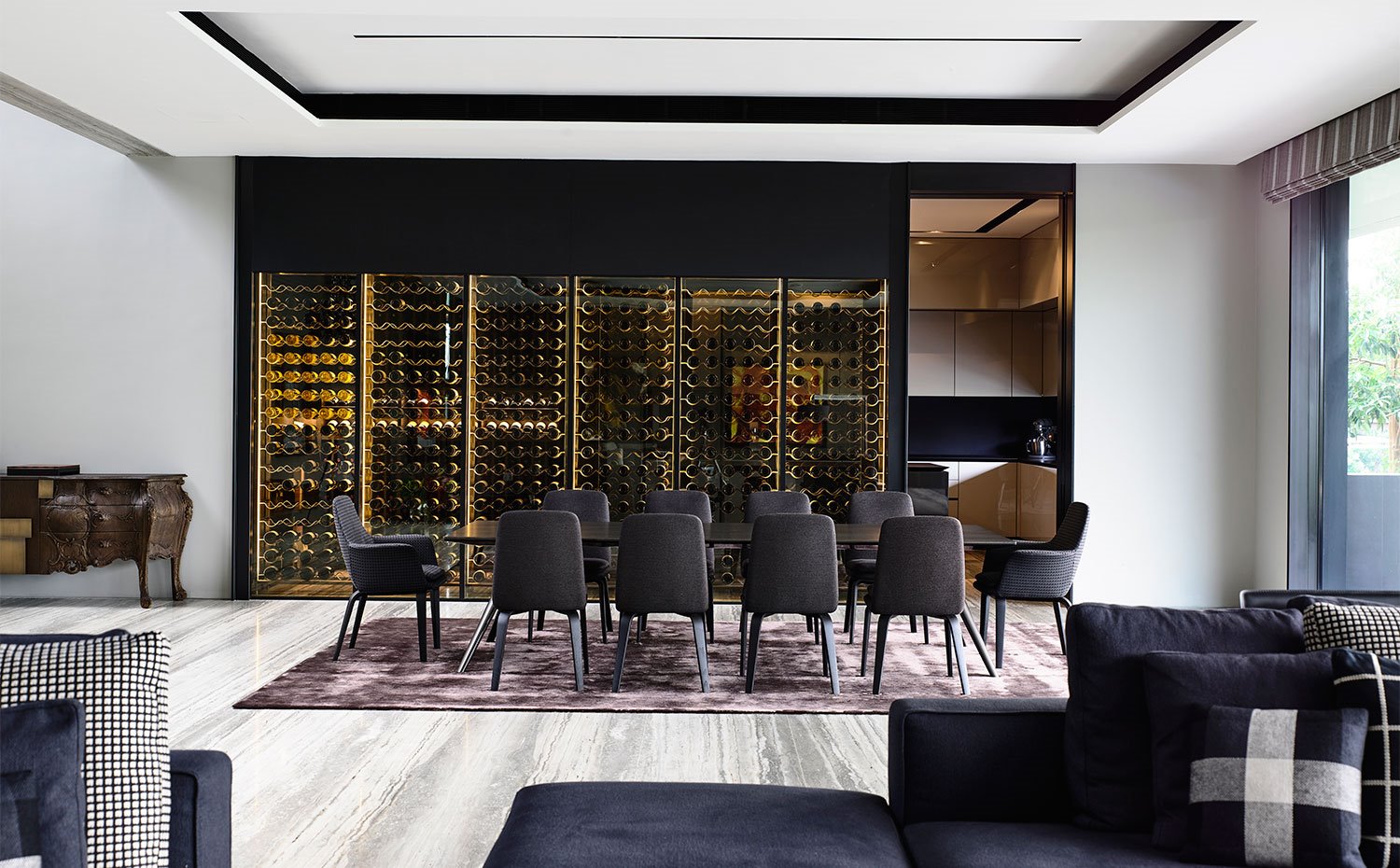 Comedor con mesa rectangular y sillas en negro, alfombra granate y botellero en frente de pared
