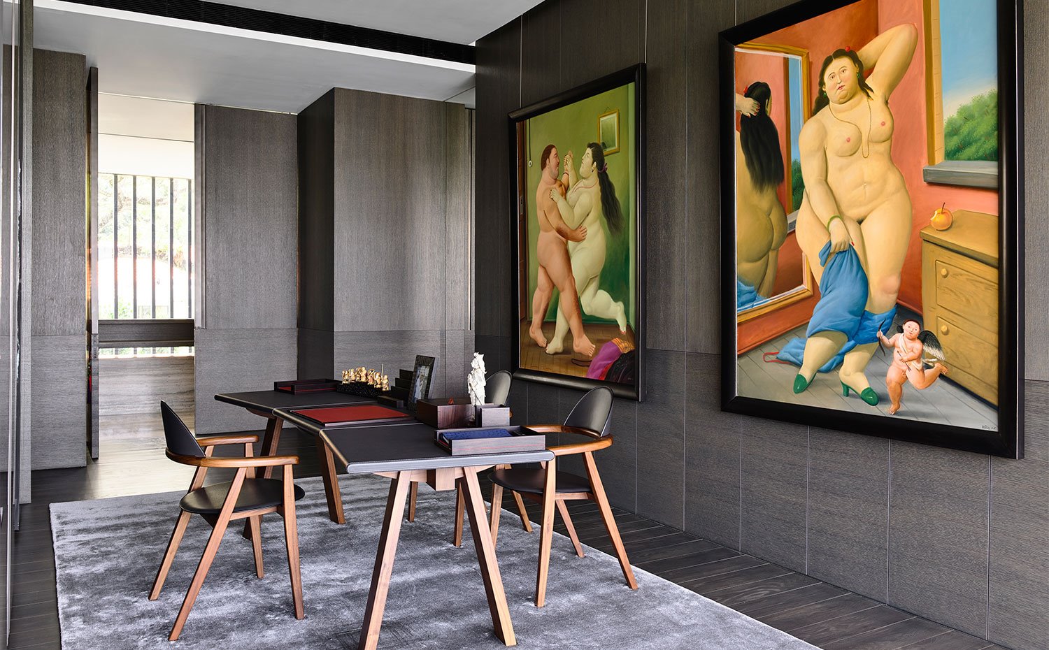 Estudio con paredes revestidas de madera, mobiliario de madera, alfombra en tonos lila, obras de arte de vivos colores