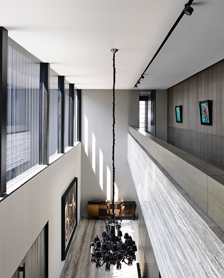 Zona de paso en piso superior con hueco a doble altura y gran luminaria suspendida de diseño victoriano