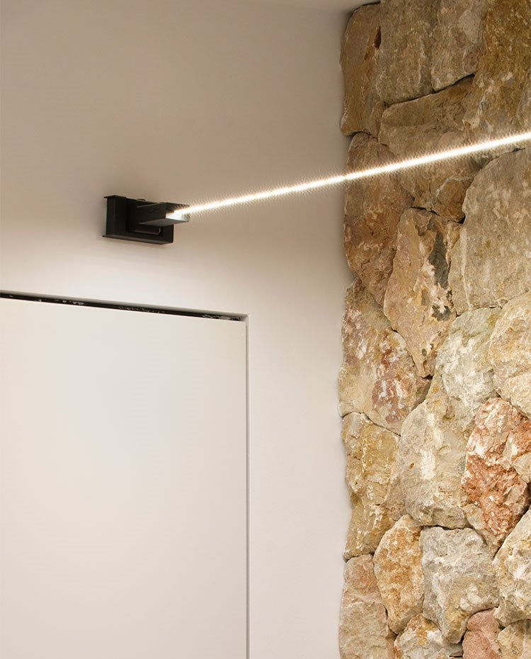 Detalle de hilo de luz de LEDs frente a la pared de piedra