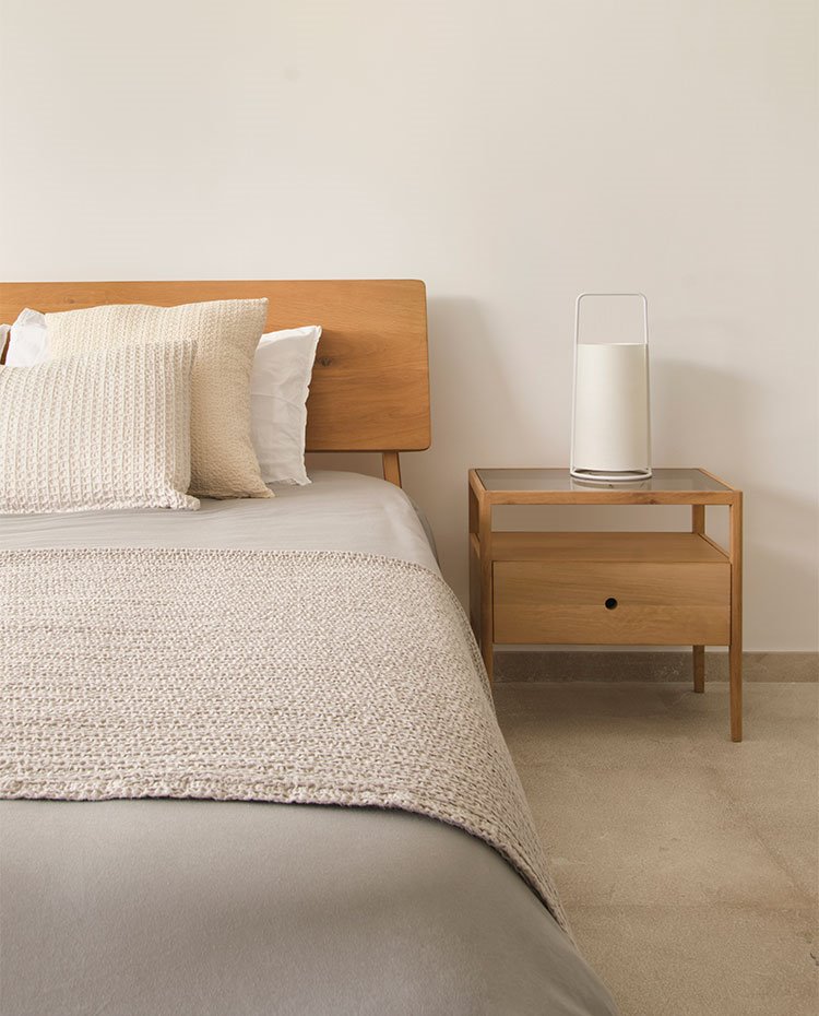 Dormitorio con cabecero y mesilla de noche en madera, luminaria de sobremesa circular