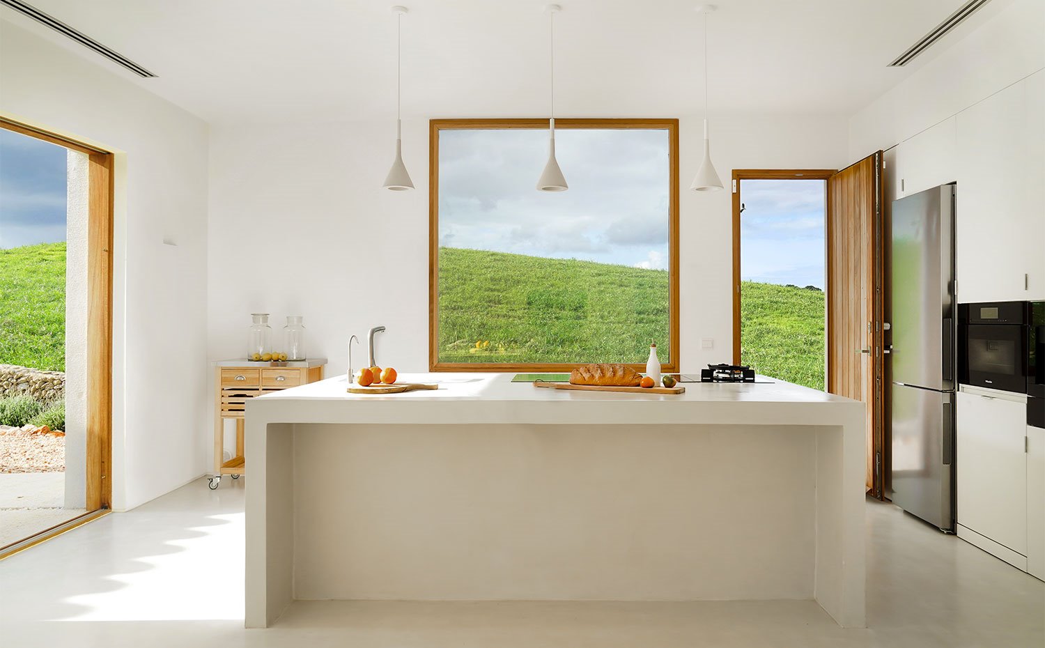 Frontal de cocina con amplia isla central y zona de almacenaje en pared