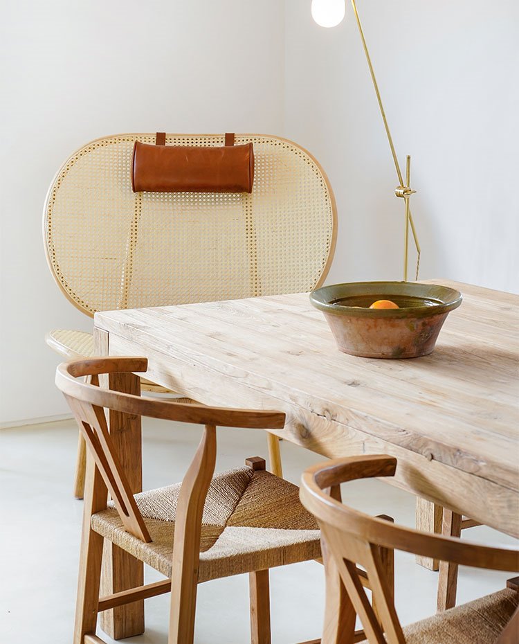 Mesa de comedor de madera con asientos en madera y fibra natural y butaca con apoyacabezas de piel