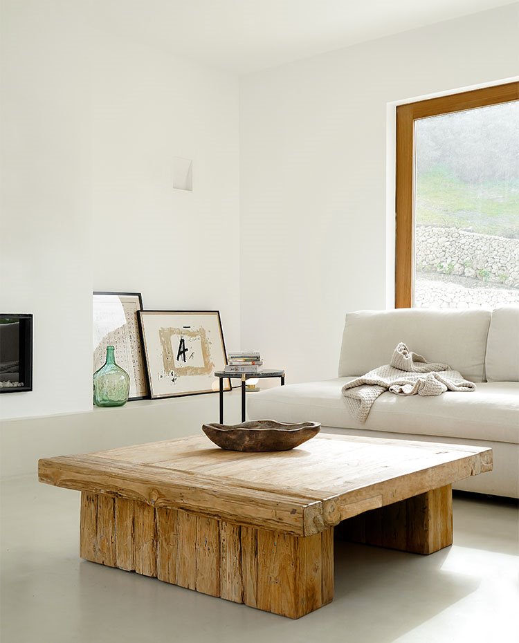 Salón con mesa de centro de madera envejecida y sofá en tonos crudos