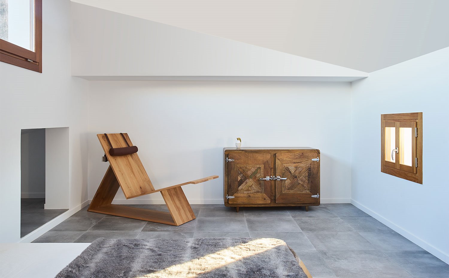 Butaca escultural de madera, ventanas con perfilería de madera, baul vintage