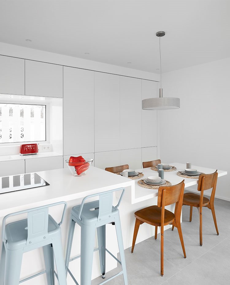 Cocina con mobiliario en blanco, isla de trabajo y zona de office