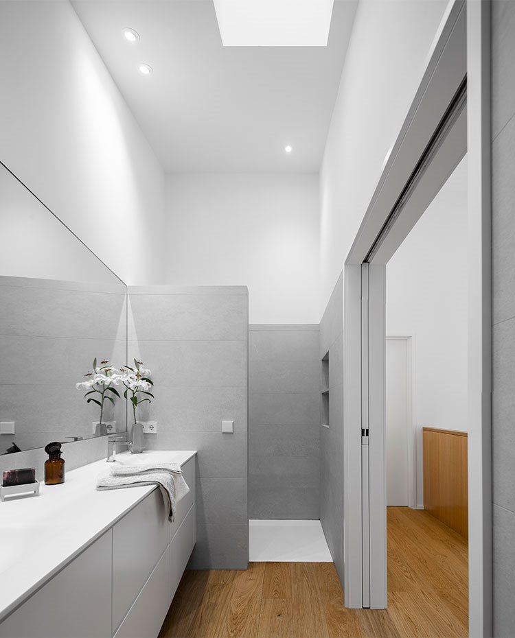 Cuarto de baño con amplia zona de ducha, tabique de separación de obra y tocador con mueble suspendido