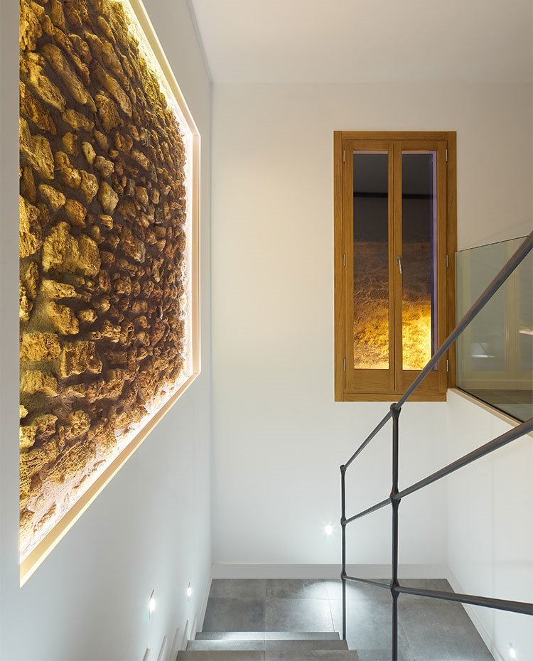 Detalle de pasamanos de hierro, perfilería de madera, pared de piedra vista