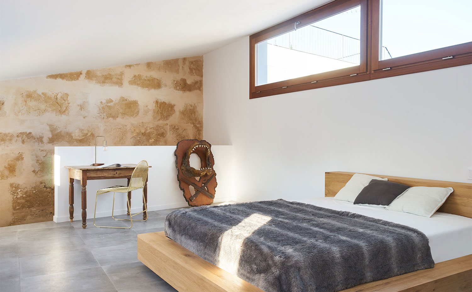 Dormitorio con estructura de cama, tipo tatami, en madera, mesa vintage, silla dorada
