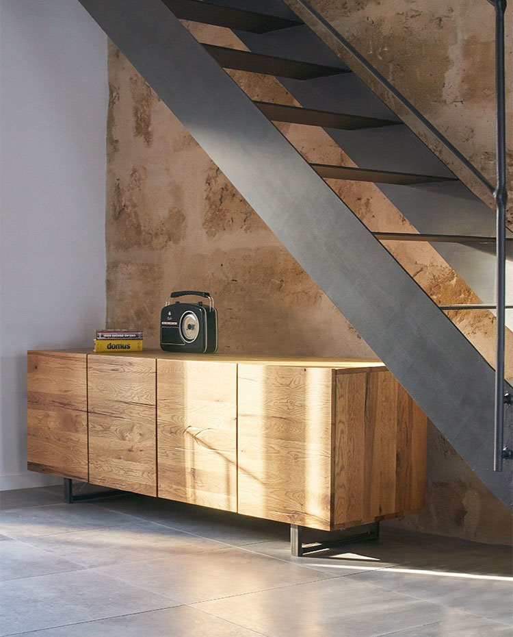 Mueble de madera bajo escaleras de acero en negro