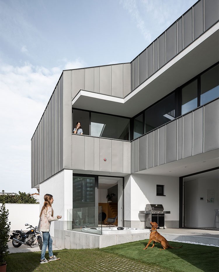 Patio exterior de vivienda con zona cubierta bajo estructura y zona ajardinada